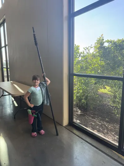 Professional window cleaning by Sparkle Window Cleaners — Isla with pole beside tall interior windows.